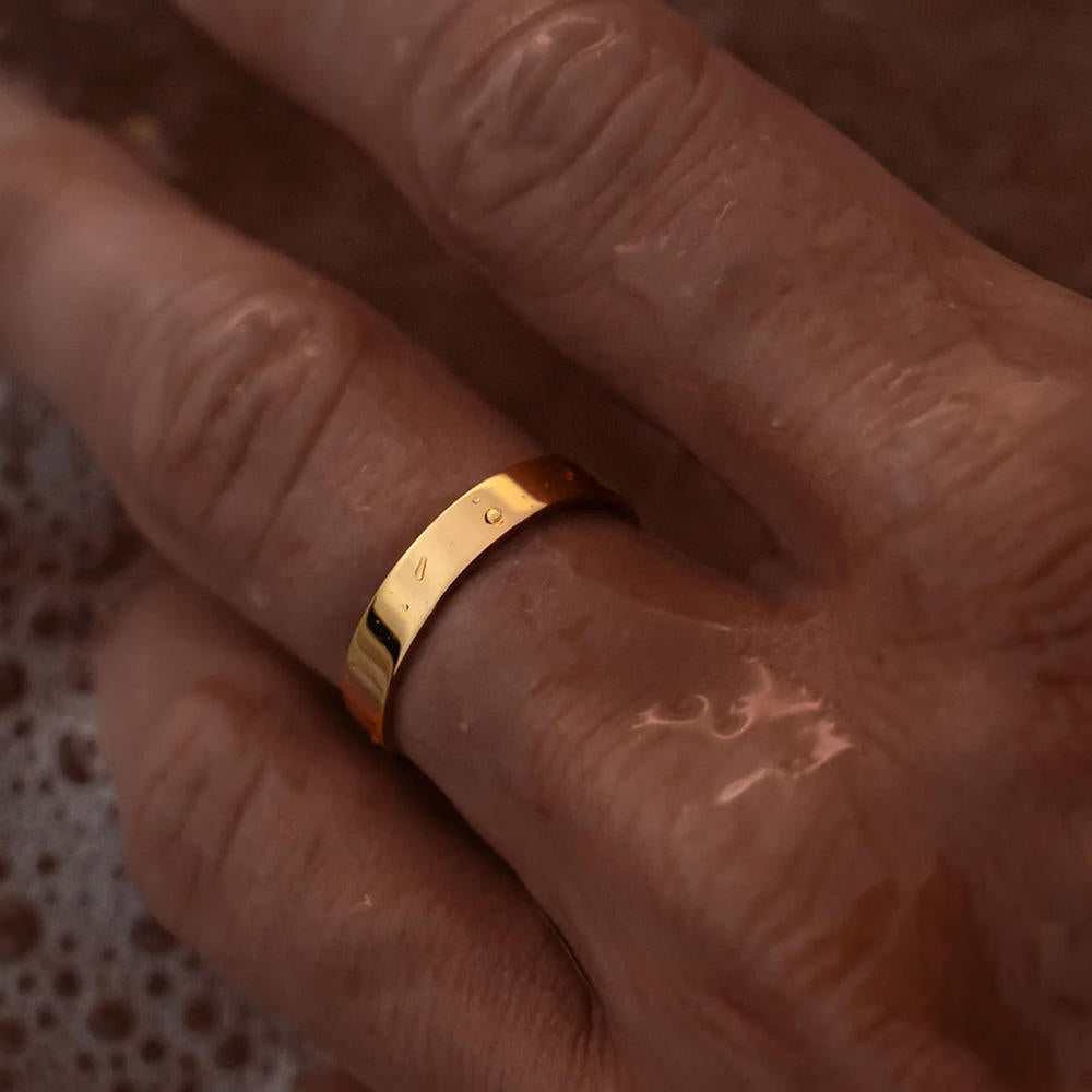 Gold ring on a person's finger with a blurred background