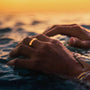 Close-up of hands with a ring in water at sunset
