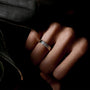 Silver ring on a person's finger with a dark background