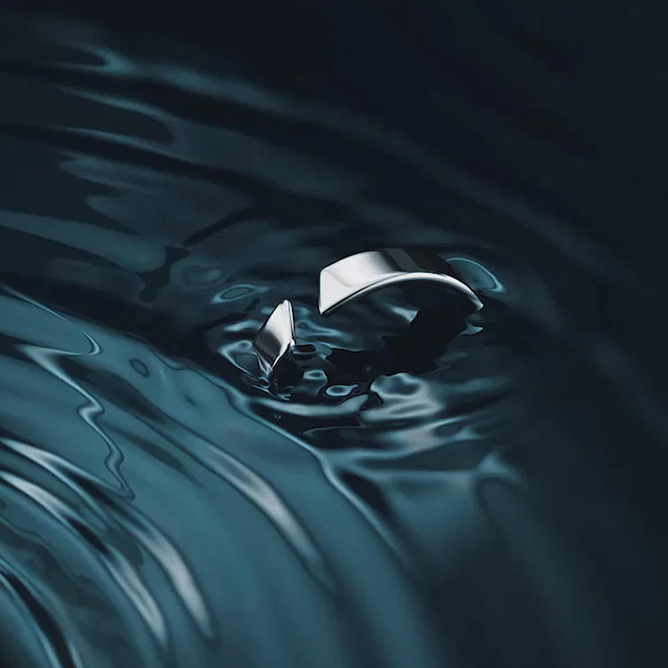 Silver ring with a unique design submerged in water, creating ripples.
