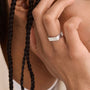 Hand wearing a silver ring with braided hair in the background