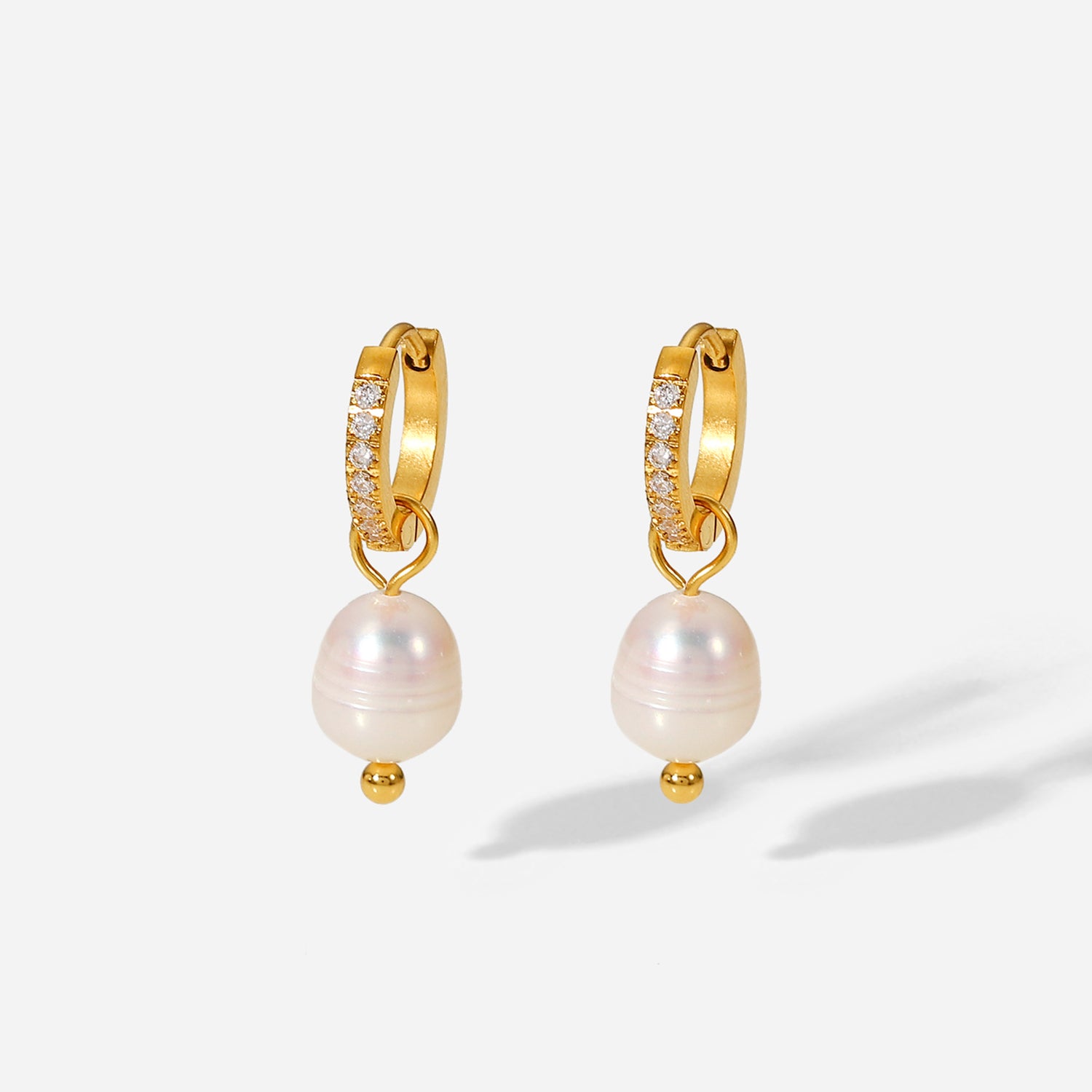 Gold hoop earrings with pearl drops on a white background