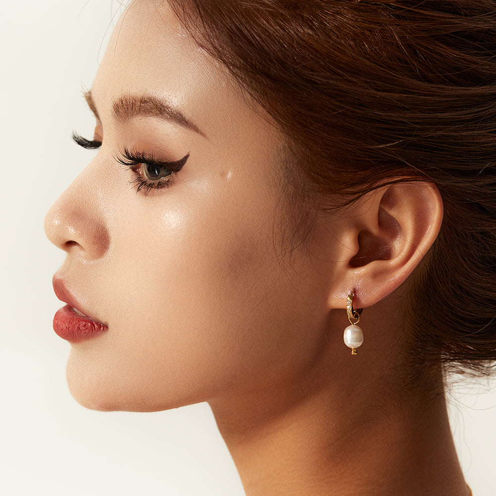 Close-up of a woman wearing a pearl earring with a plain background