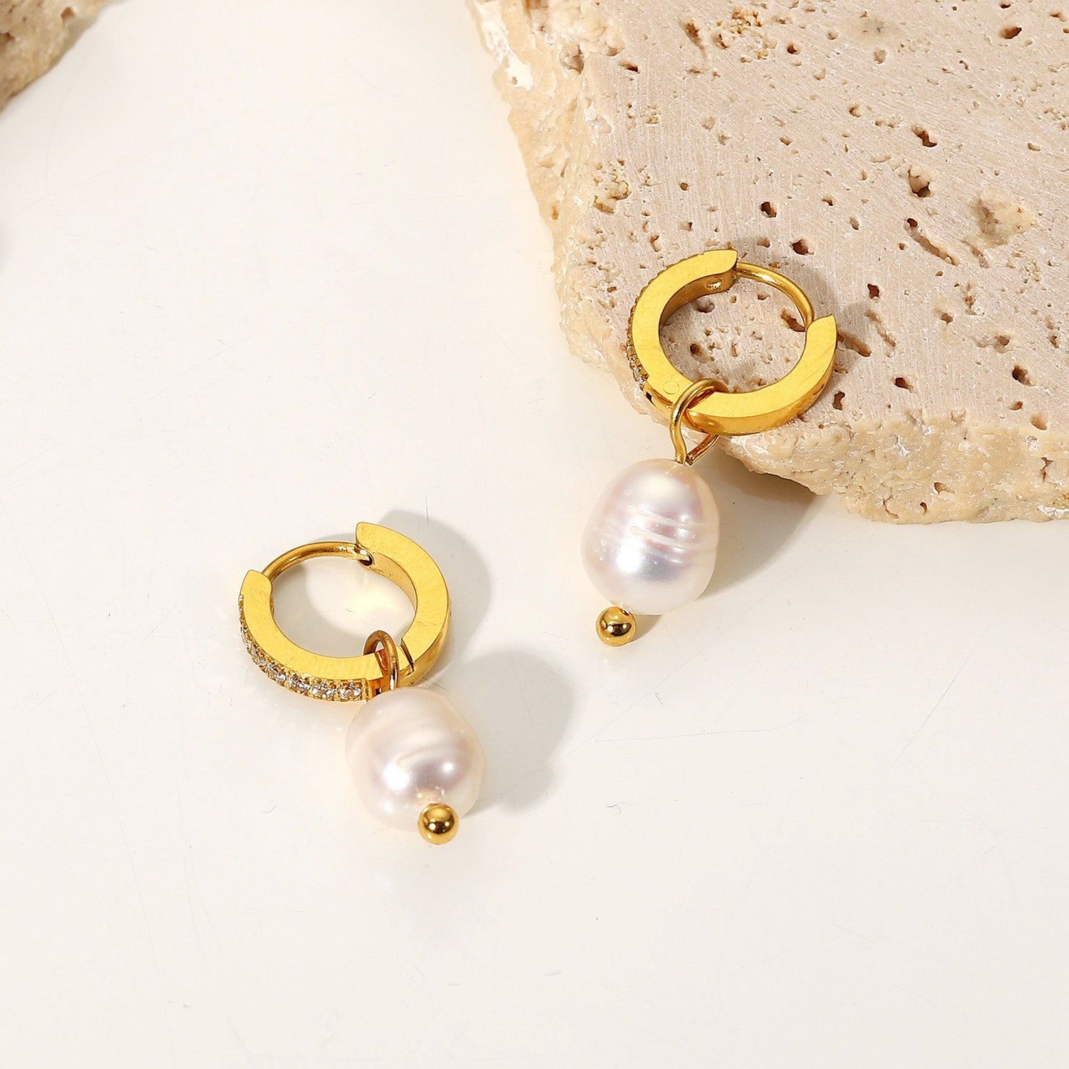 Gold hoop earrings with pearls on a light background