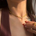 Close-up of a person wearing a gold necklace and ring with a blurred background