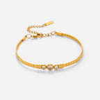 Gold bracelet with three circular charms on a light beige background