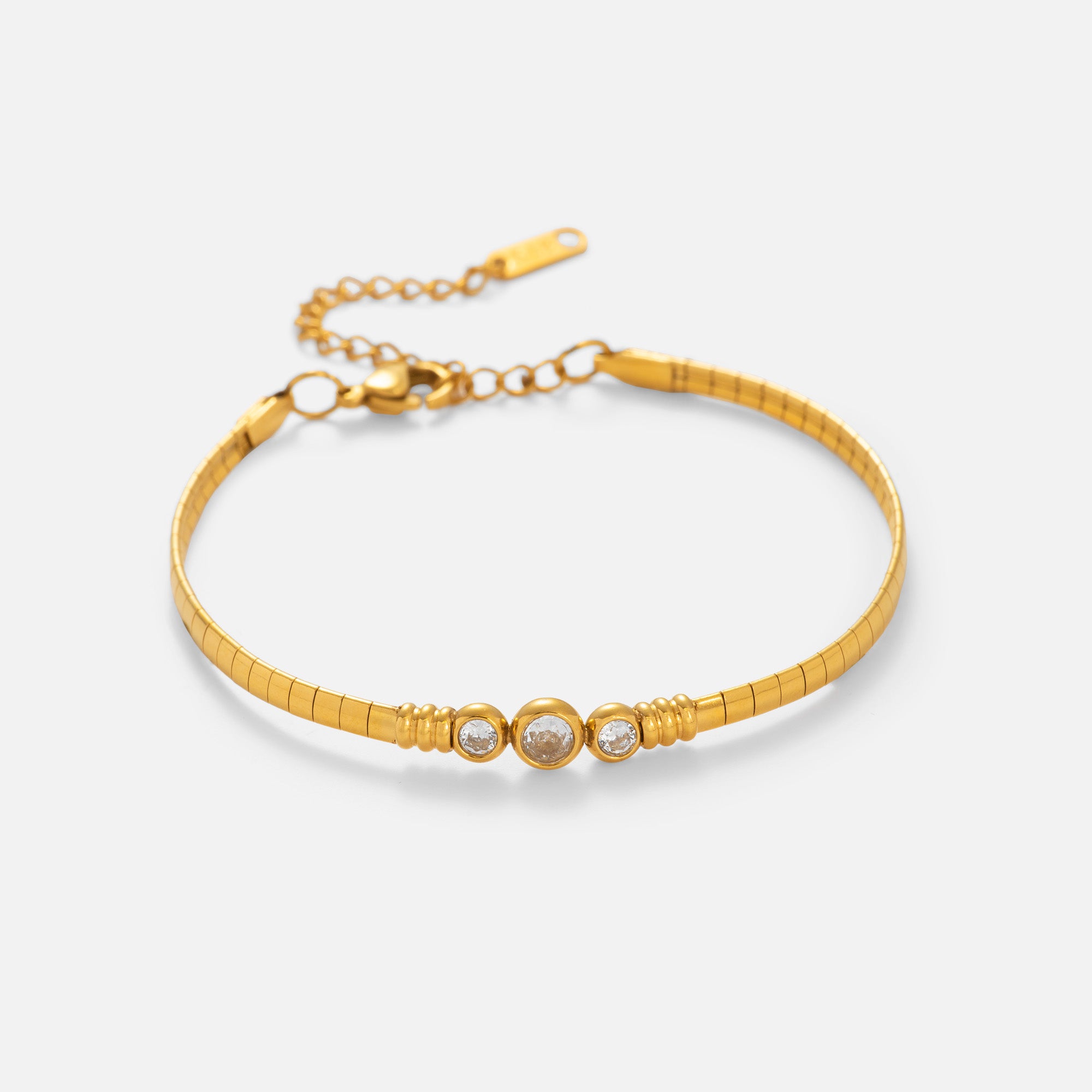 Gold bracelet with three circular charms on a light beige background