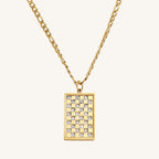 Gold necklace with a rectangular pendant featuring a checkered pattern on a white background