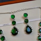 Green gemstone jewelry set with silver chain on a white background