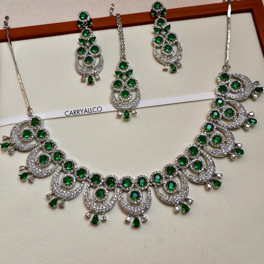 Jewelry set with green stones on a white and pink background