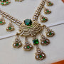 Ornate necklace with green gemstones on a light background