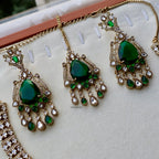 Green gemstone earrings with gold accents on a white surface
