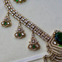 Ornate gold necklace with green gemstones on a light background