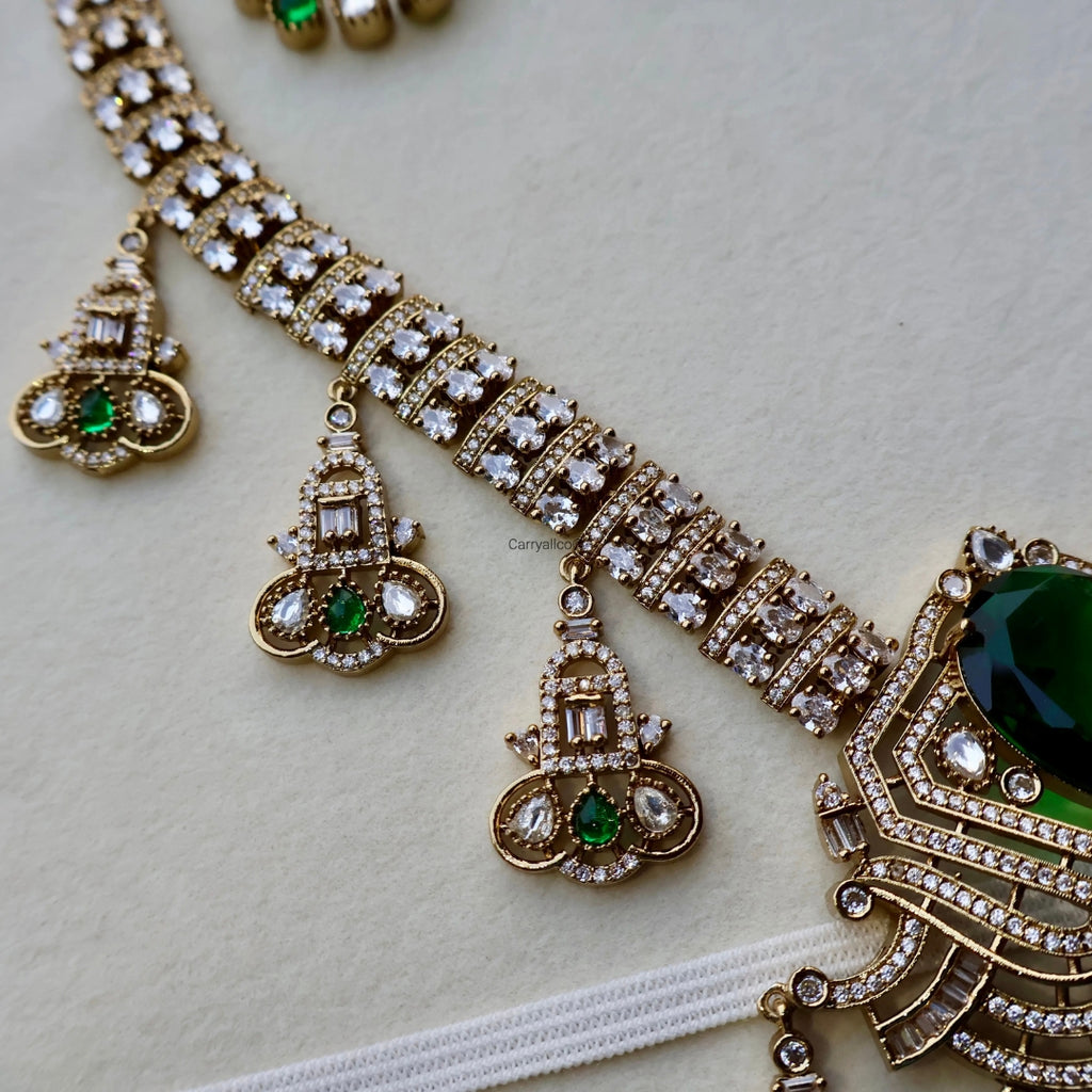 Ornate gold necklace with green gemstones on a light background