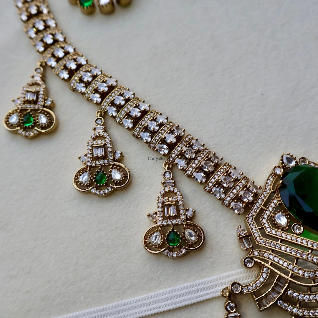 Ornate gold necklace with green gemstones on a light background