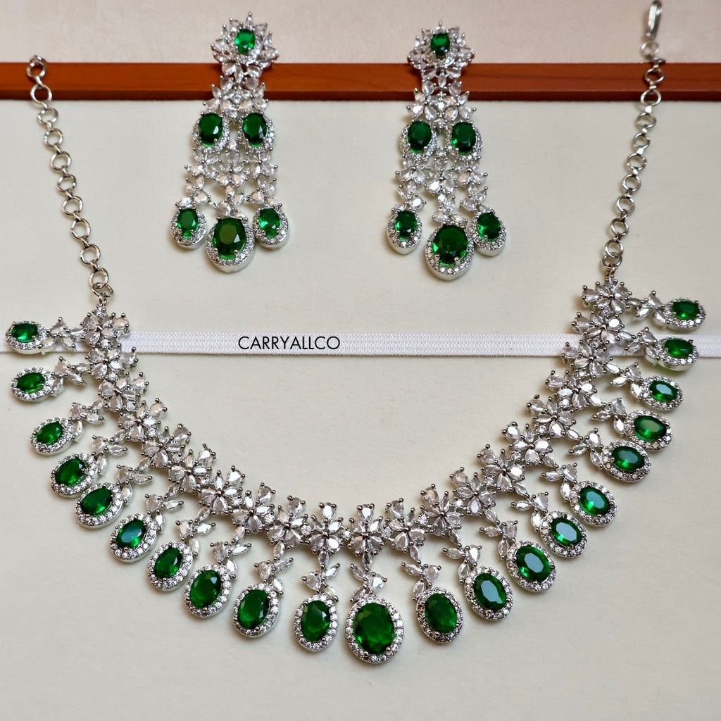 Necklace and earrings set with green gemstones on a white background