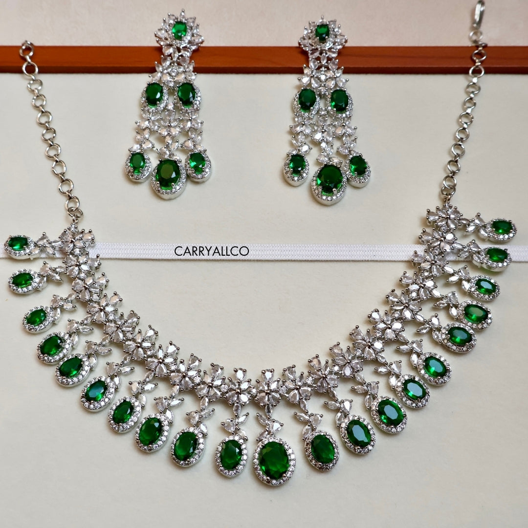 Necklace and earrings set with green gemstones on a white background