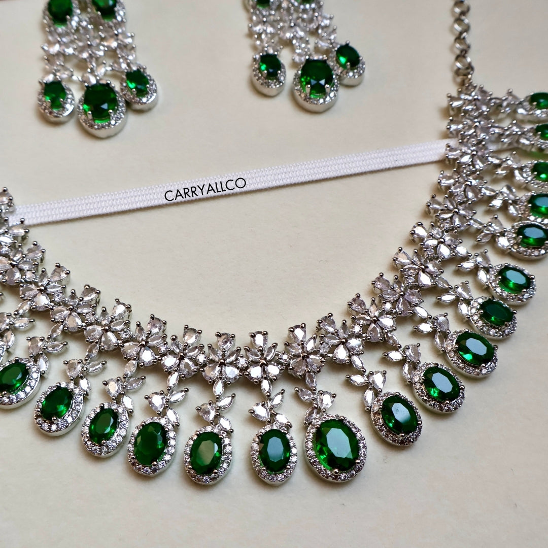 Jewelry set with emerald green stones and silver accents on a white background, featuring the brand 'CARRYALLCO'.