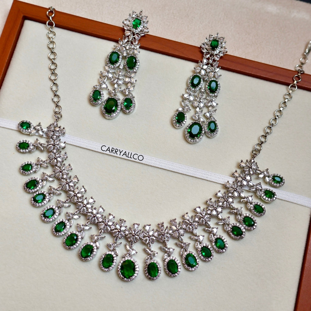 Jewelry set with necklace and earrings featuring green gemstones on a white background.