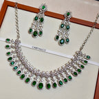 Jewelry set with necklace and earrings featuring green gemstones on a white background.