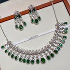 Jewelry set with necklace and earrings featuring green gemstones on a white background.