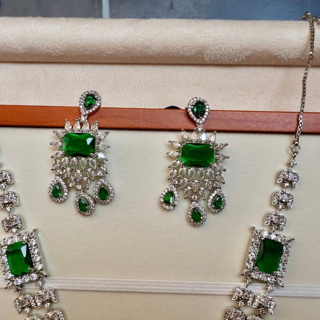 Jewelry set with green gemstones on a beige surface