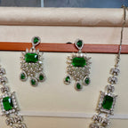 Jewelry set with green gemstones on a beige surface