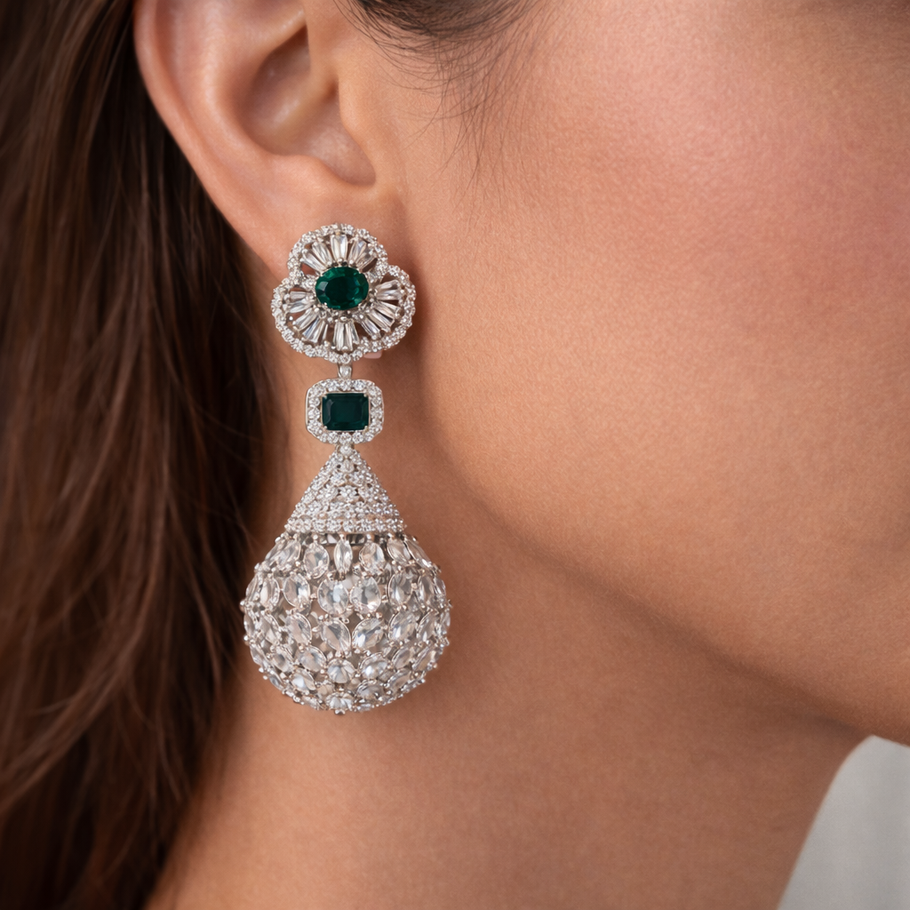 Close-up of a woman wearing an elegant earring with green gemstones.