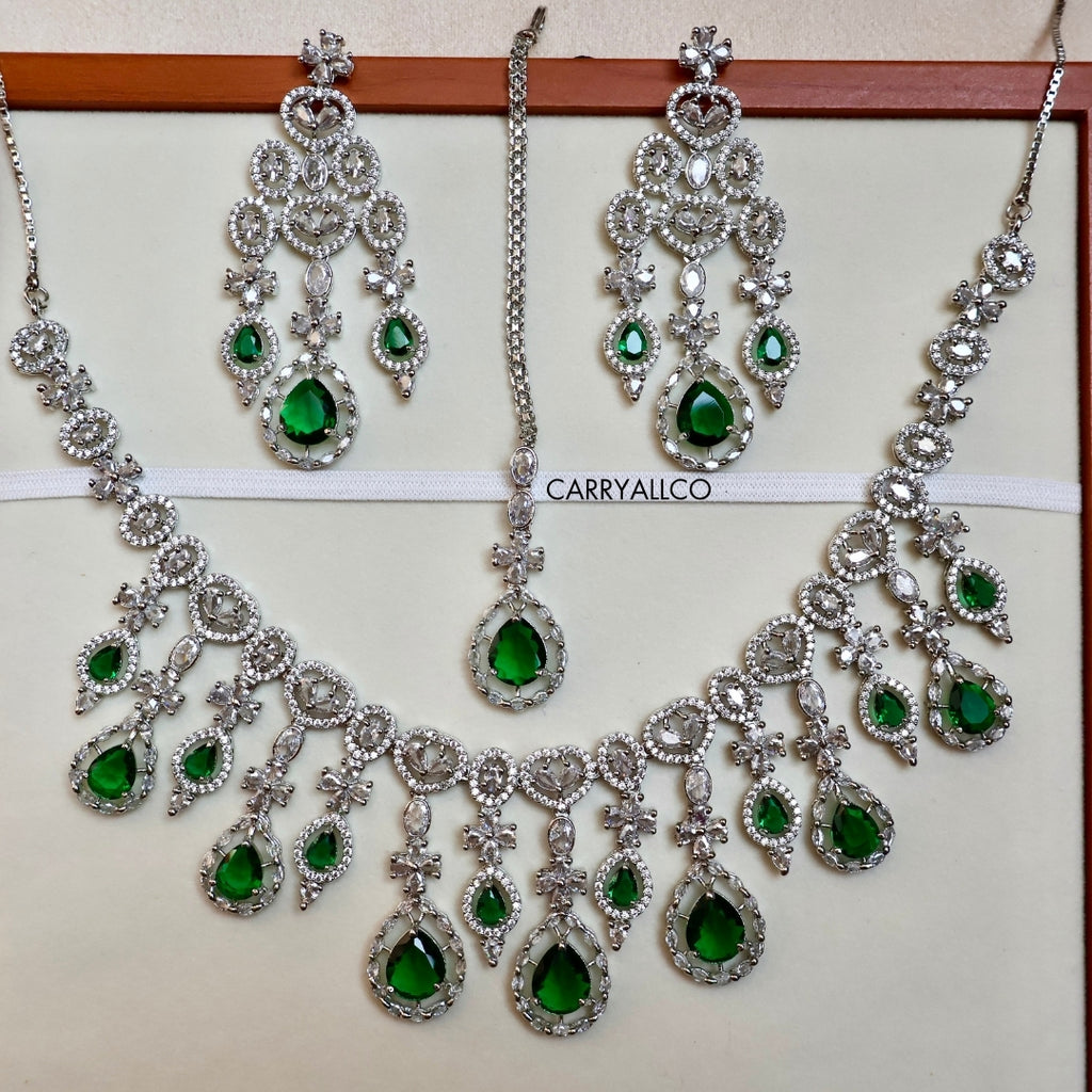 Jewelry set with necklaces and earrings featuring green gemstones on a white background.