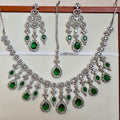 Jewelry set with necklaces and earrings featuring green gemstones on a white background.