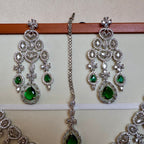 Silver jewelry set with green gemstones on a beige background