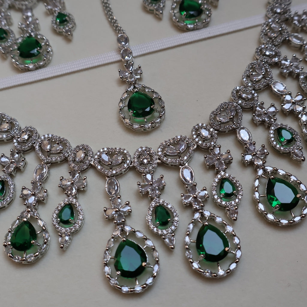 Jewelry set with green gemstones and silver accents on a light background