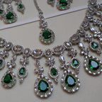 Jewelry set with green gemstones and silver accents on a light background