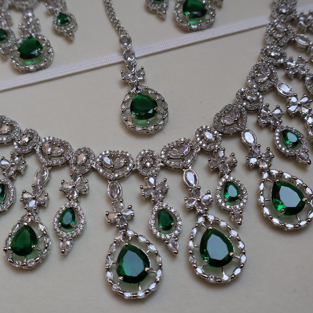 Jewelry set with green gemstones and silver accents on a light background