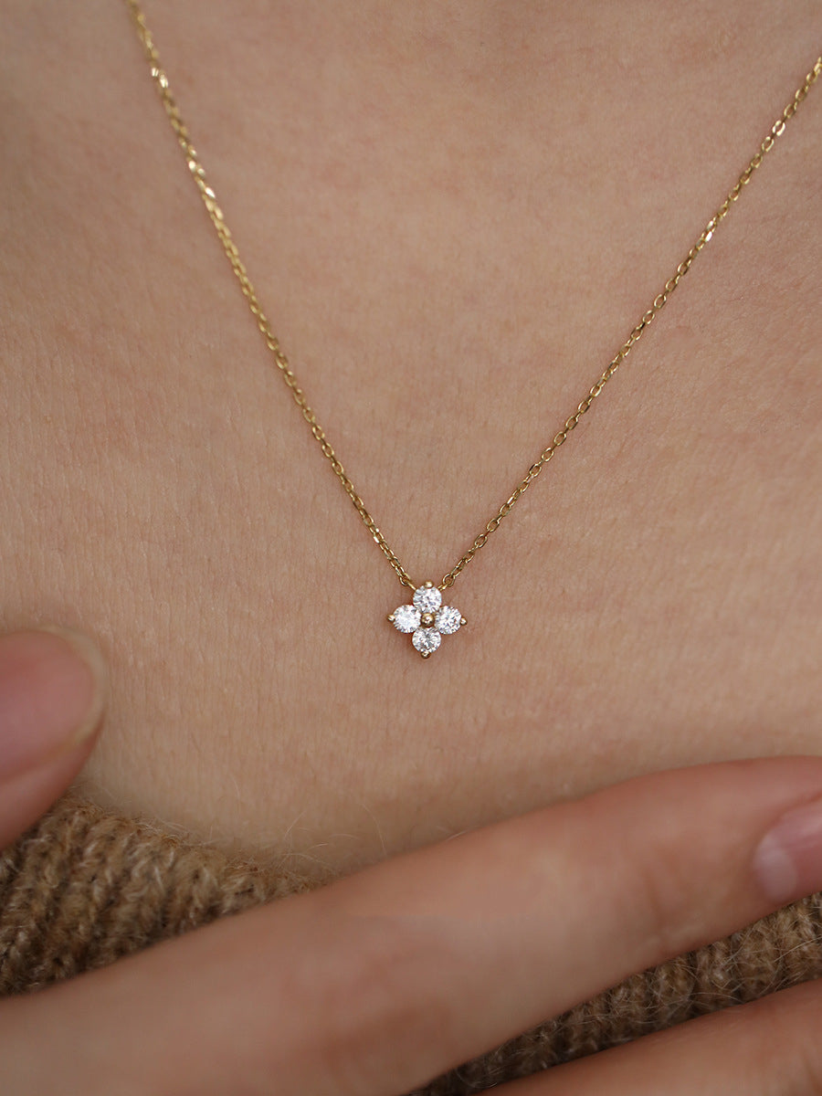 Gold necklace with a small floral pendant on a person's neck.