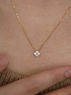 Gold necklace with a small floral pendant on a person's neck.