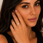 Woman wearing a gold ring with a diamond, touching her face.