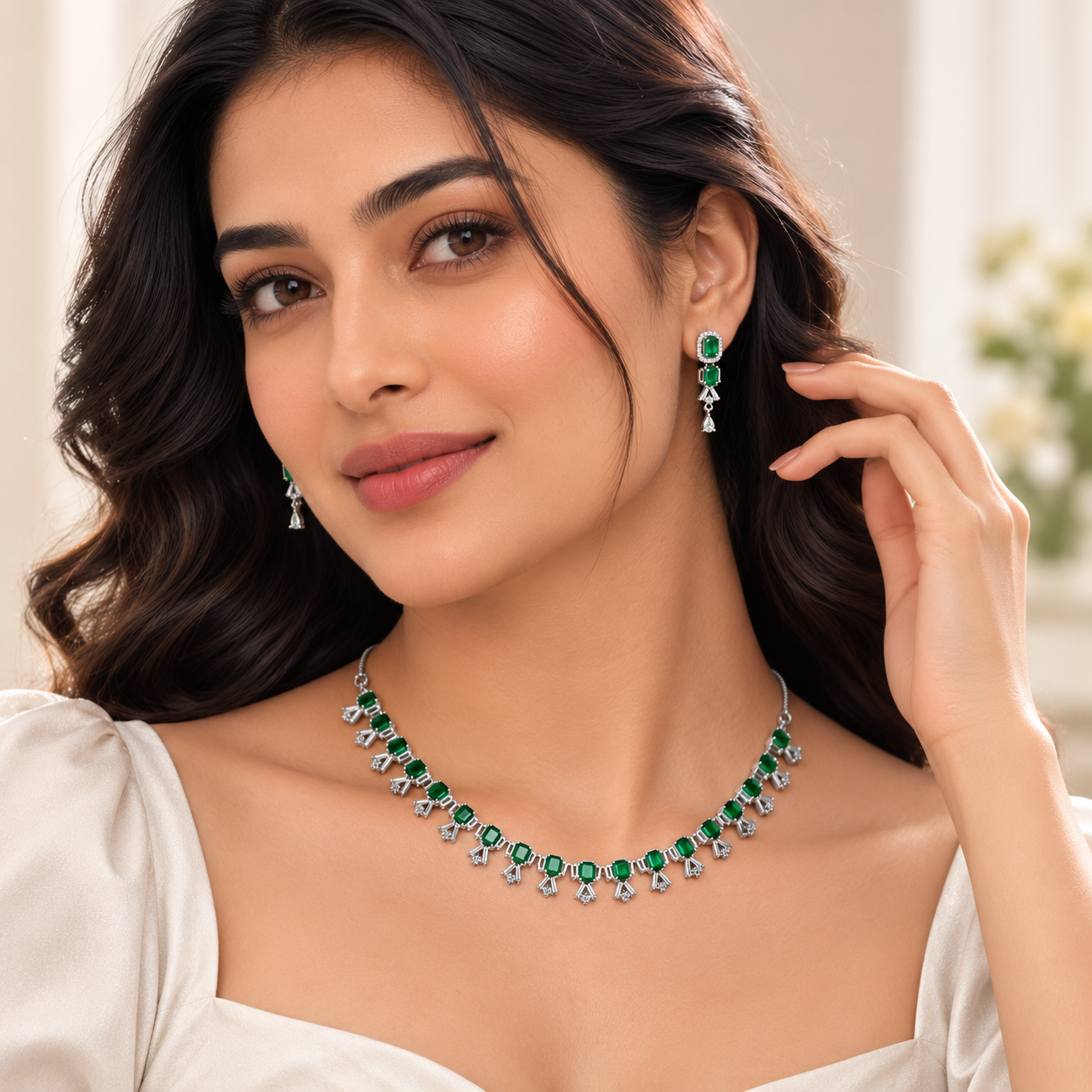 A woman wearing a matching emerald green and silver jewelry set, featuring a necklace and matching drop earrings, styled with a white off-the-shoulder top.