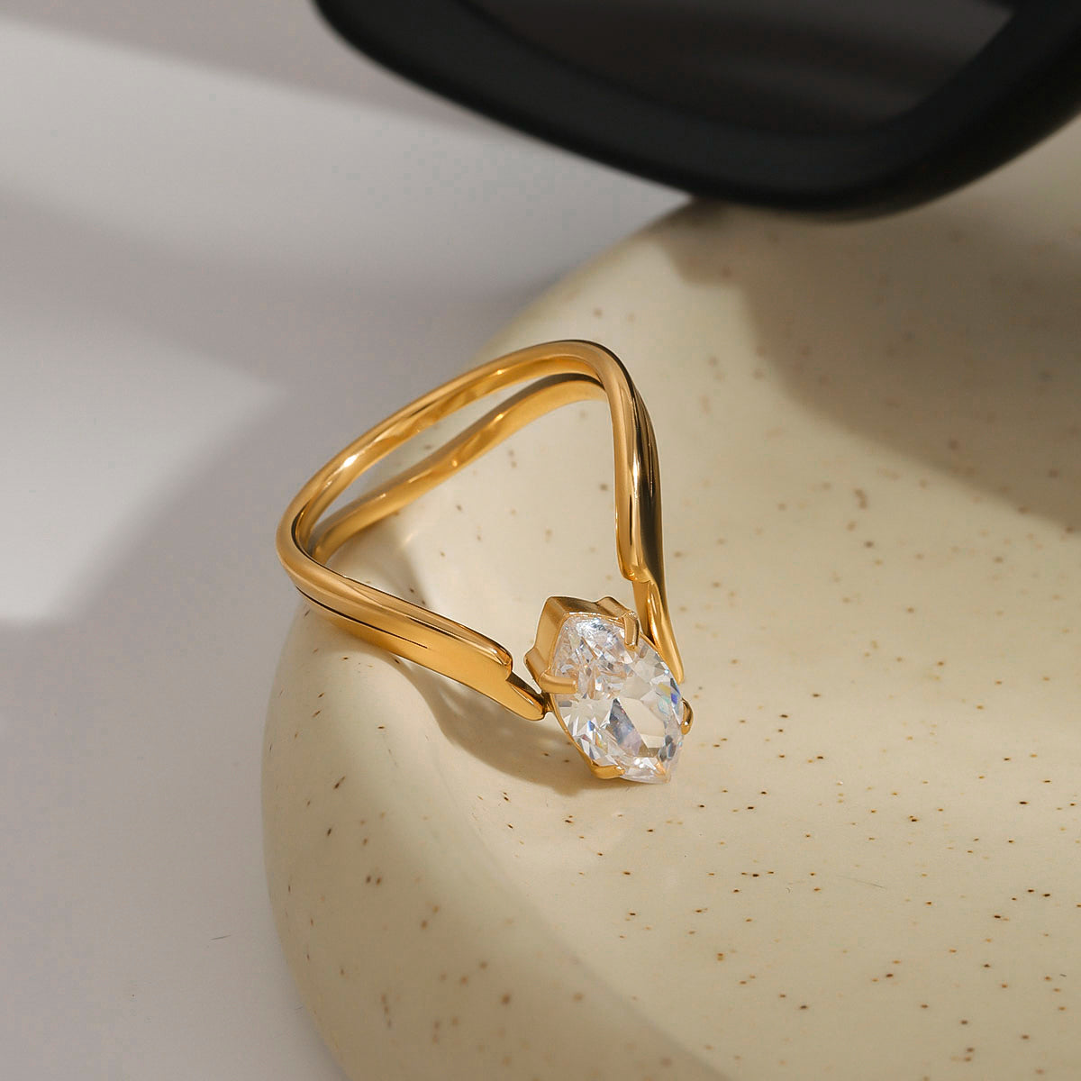 Gold ring with a diamond on a beige surface