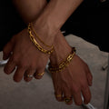 Close-up of hands wearing multiple gold bracelets and rings on a neutral background