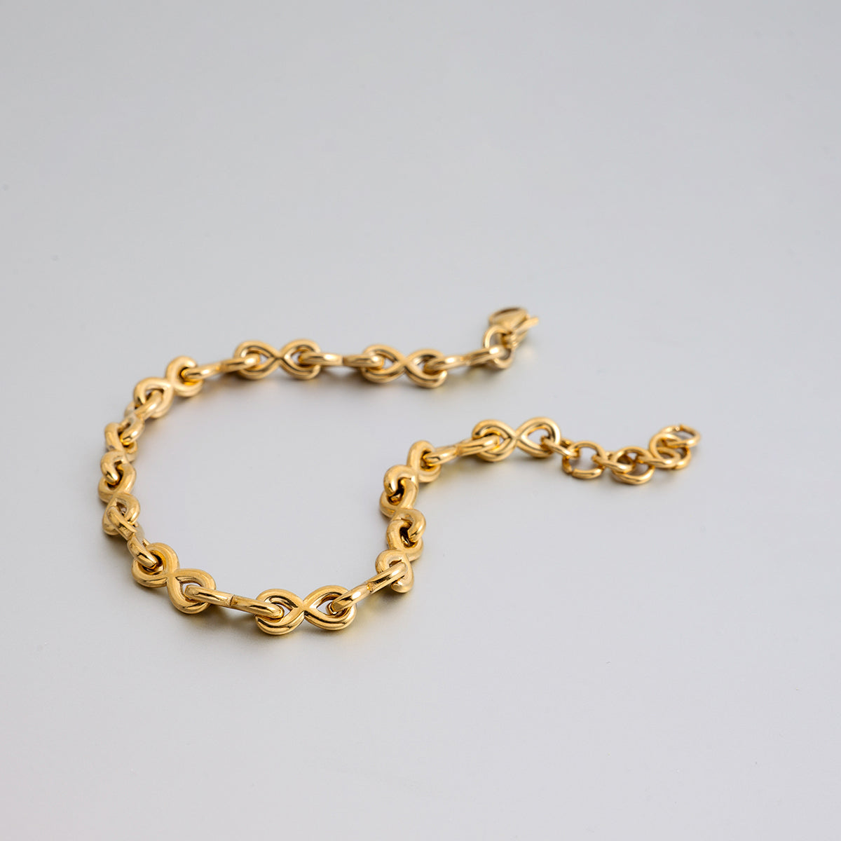 Gold chain bracelet on a light gray background