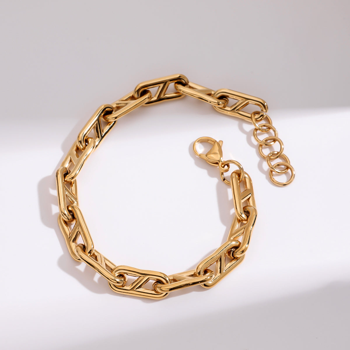 Gold chain bracelet on a light gray background
