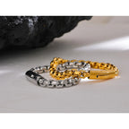 Two chain bracelets, one silver and one gold, on a light surface.