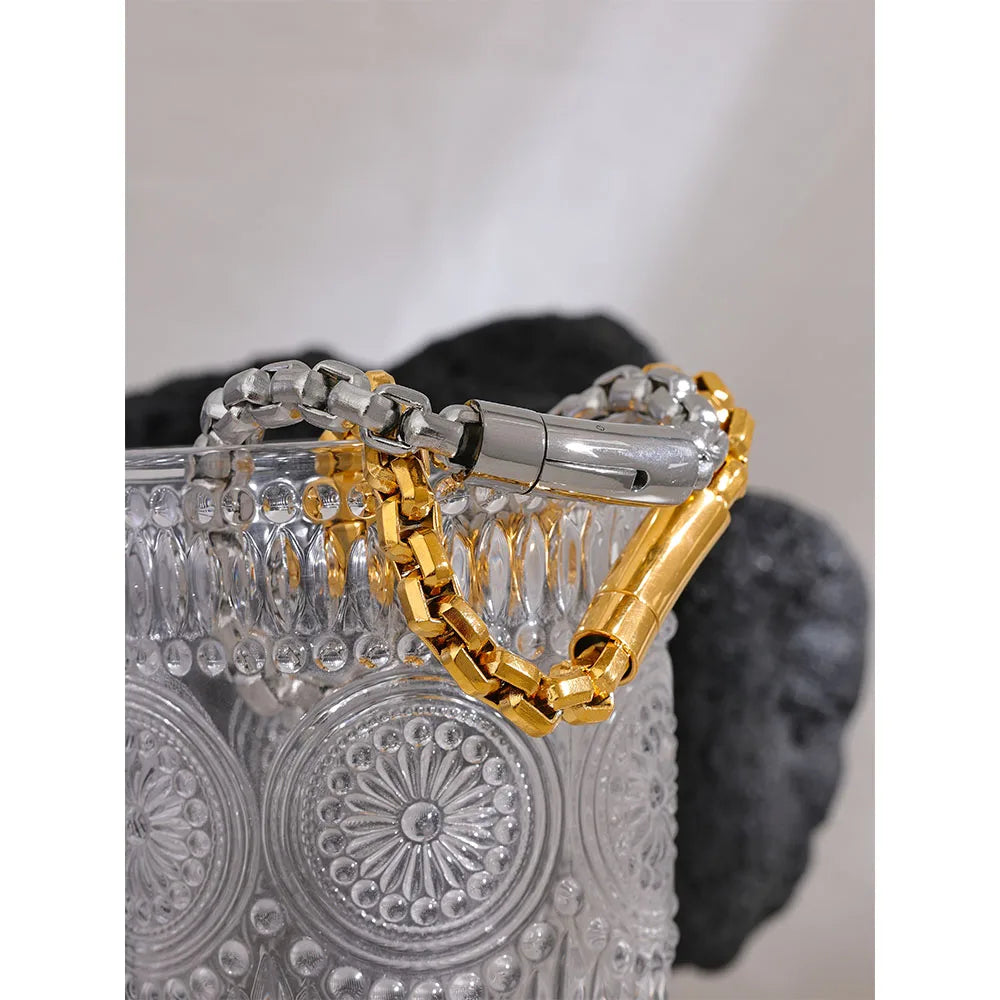 Gold and silver chain bracelet on a textured surface