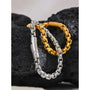 Two bracelets, one gold and one silver, on a textured black surface.