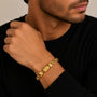 Man wearing a gold bracelet on his wrist against a neutral background