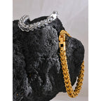 Gold and silver chain bracelets on a dark stone surface