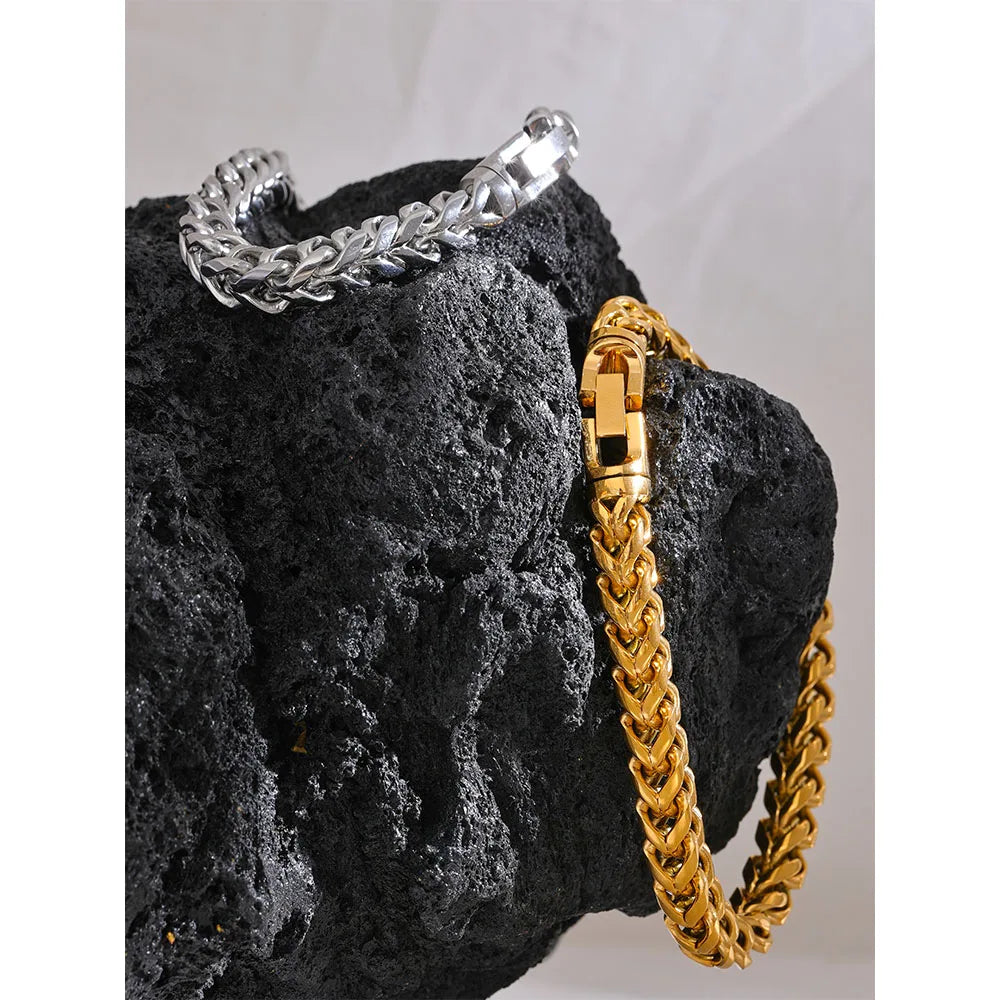Gold and silver chain bracelets on a dark stone surface