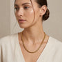Woman wearing a gold chain necklace against a neutral background