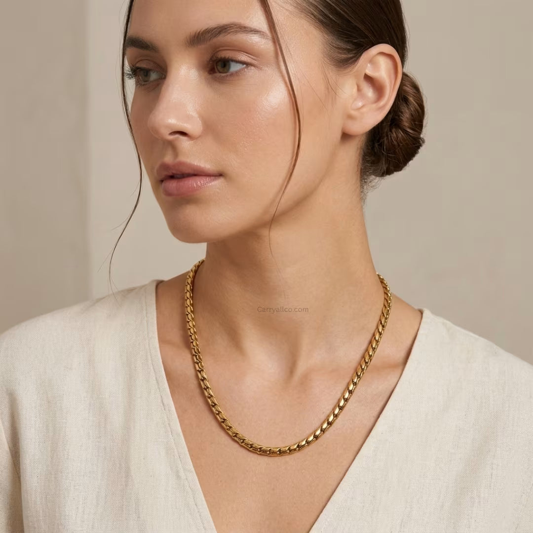 Woman wearing a gold chain necklace against a neutral background